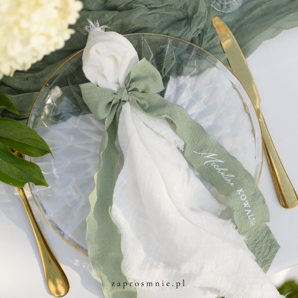 Elegancka winietka ślubna w formie materiałowej wstążki w kolorze zielonym z nadrukowanym białym, przewiązana kokardą przy kieliszku, nowoczesna i nietuzinkowa dekoracja stołu weselnego, hit Pinterest i wyjątkowa alternatywa dla klasycznych winietek.