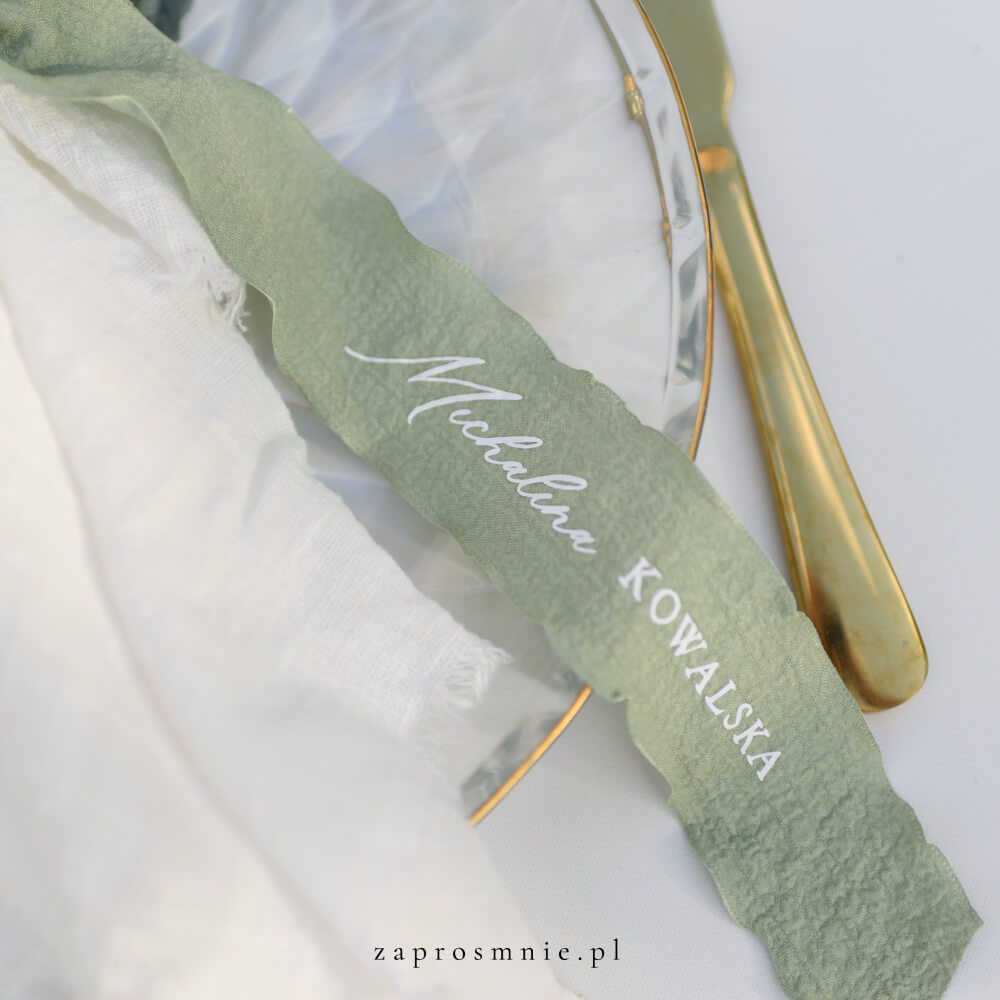 Elegancka winietka ślubna w formie materiałowej wstążki w kolorze zielonym z nadrukowanym białym, przewiązana kokardą przy kieliszku, nowoczesna i nietuzinkowa dekoracja stołu weselnego, hit Pinterest i wyjątkowa alternatywa dla klasycznych winietek.