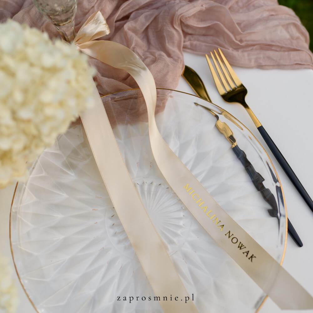 Elegancka winietka ślubna w formie ecru satynowej wstążki z nadrukowanym białym, przewiązana kokardą przy kieliszku, nowoczesna i nietuzinkowa dekoracja stołu weselnego, hit Pinterest i wyjątkowa alternatywa dla klasycznych winietek.