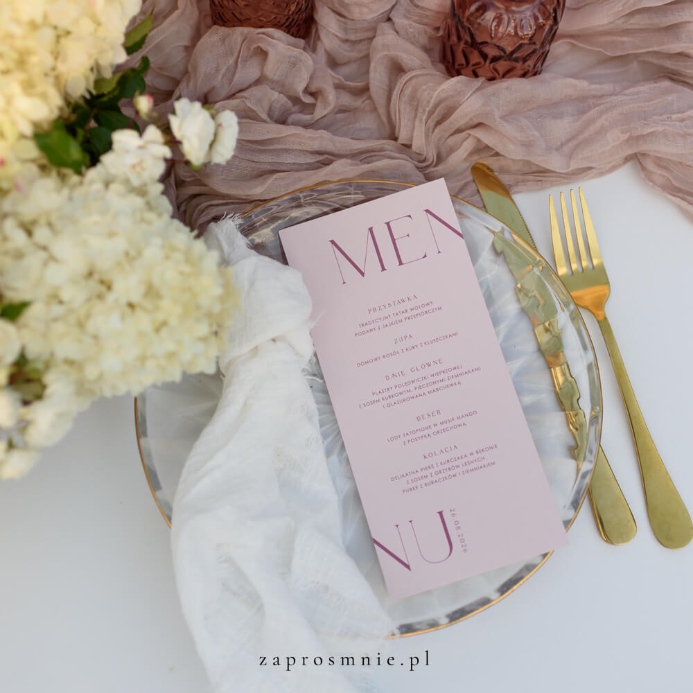 Eleganckie menu weselne w pastelowym odcieniu różu, położone na przezroczystym talerzu ze złotymi sztućcami, minimalistyczny design z nowoczesną typografią, personalizowana papeteria ślubna podkreślająca wyjątkowy charakter przyjęcia, idealne uzupełnienie dekoracji stołu weselnego i spójnej aranżacji ślubu.